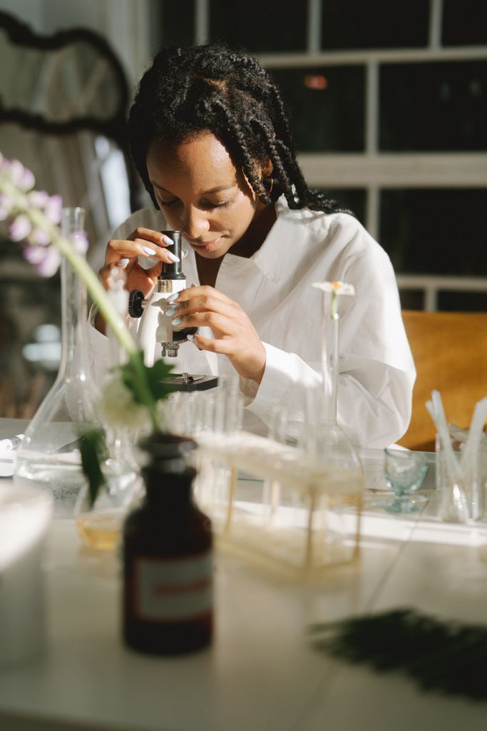 A dedicated female scientist examining specimens under a microscope in a well-equipped laboratory.